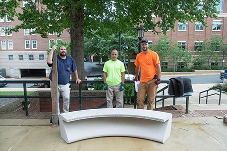 Three FM workers stand behind a newly-installed bench