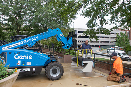FM workers installing a stone bench with a forklift
