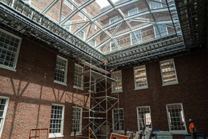 A construction worker stands on a scaffold beneath large domed skylights