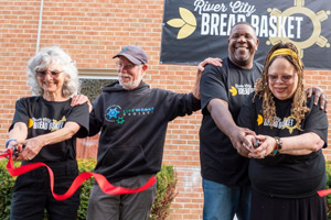 AJ Young and his wife Adrienne cutting a ribbon to open a food pantry