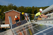 Workers install solar panel system on Leake II roof