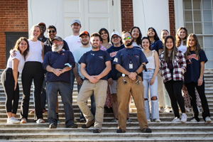 Electricians stand with student volunteers on the stairs of the Rotunda