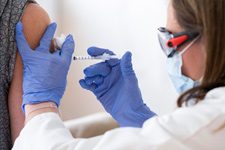 A medical worker administering an injection to someone's arm