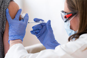 A medical worker administering an injection to someone's arm