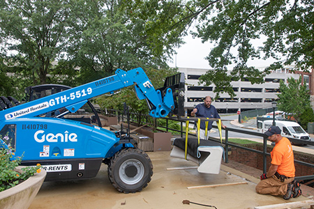 FM workers installing a stone bench with a forklift