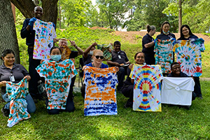 Custodial employees holding up tie-dyed shirts