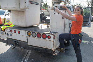 FM employee with a leg up on a cherry picker truck, wearing a new style of workwear