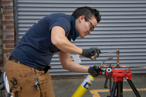 FM employee welding copper pipe while wearing a new women's workwear style