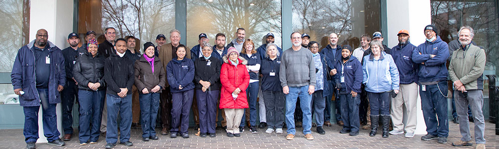 Group photo of many Facilities employees of all levels, with Gary Wood in the foreground