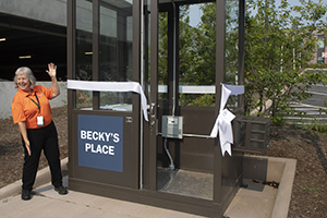 Becky Padgett waves to the camera next to a parking booth with the sign Becky's Place