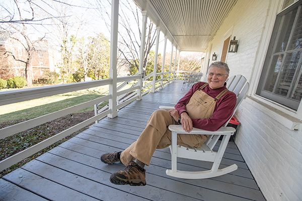 John Sauer sits in a  rocking chair on a porch