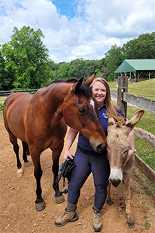 Abby Tanner stands with a horse and donkey
