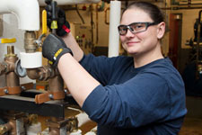 Facilities Management employee Kristina Williams adjusts a pipe