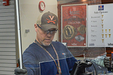 An FM employee installs a plexiglass shield at a cash register