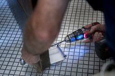 FM employee attaching a foot pull to a door with a power drill