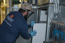 An FM employee installs a high-efficiency filter into an air-handling unit