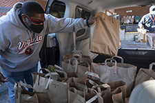 An FM employee loads food bags into an FM fleet vehicle