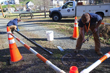 Facilities employees access a manhole cover