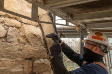 A Facilities Management employee repoints mortar in a stone wall