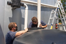 Two FM employees securing PVC pipes to a rainwater cistern