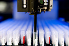 Close-up of a robot pipetting a saliva specimen from a test tube