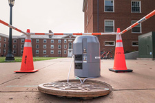 A manhole outside UVA residence halls is accessed by a wastewater sampling device