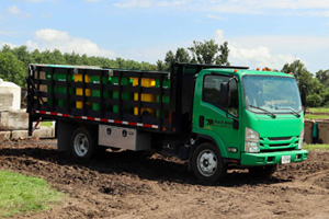 A truck with Black Bear Composting's logo carries several yellow and green bins