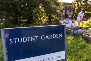 A sign in the foreground reads 'Student Garden' and students can be seen in the background tending to plants