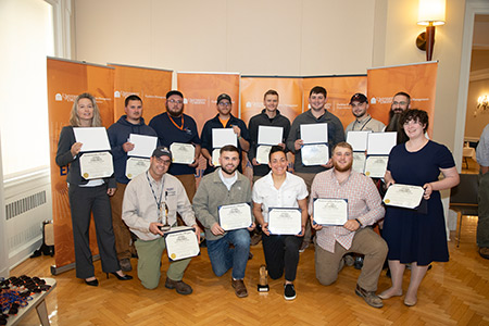 Graduates of UVA's Apprenticeship Program in a group photo holding up their diplomas