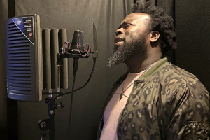 Lester Jackson sings into a microphone in a recording booth