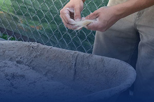 Close-up photo of a craftsperson mixing goat hair into a wheelbarrow of plaster