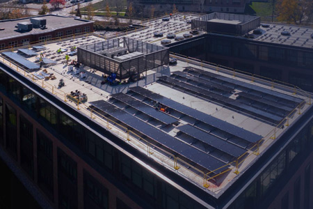 Aerial view of a building rooftop with an array of solar panels