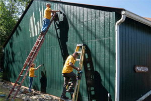 Members of Facilities Management put a fresh coat of paint on a building at Camp Holiday Trails