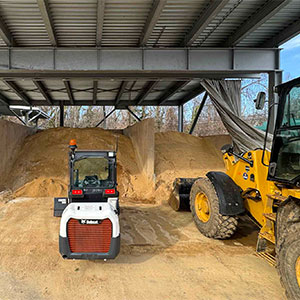 A skid-steer loader stands ready to start scooping sand and salt onto Facilities Management's trucks to deal with Tuesday's predicted snowfall.