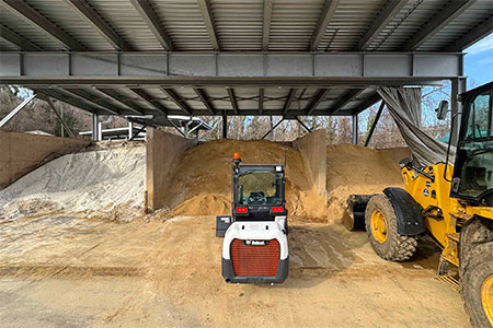 A skid-steer loader stands ready to start scooping sand and salt onto Facilities Management's trucks to deal with Tuesday's predicted snowfall.