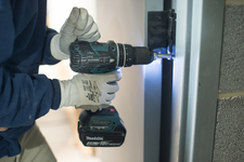 A construction worker installing a door hinge
