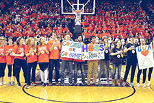 Student volunteers holding sustainability posters line up on basketball court