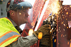 Energy & Utilities employee using a grinder on steel.