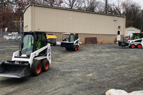 Facilities Management trainees driving Bobcats on a gravel lot