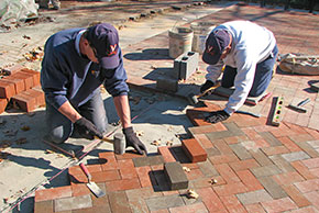 Masons replacing brick walkway