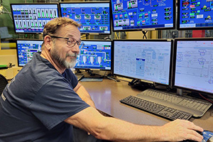 Tracy Saul at a desk with several computer monitors